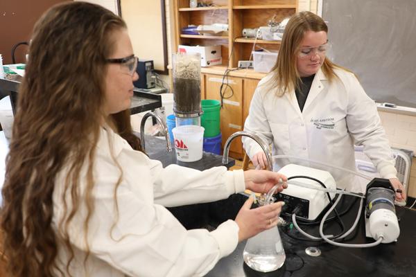 Two female students using environmental engineering equipment in a lab